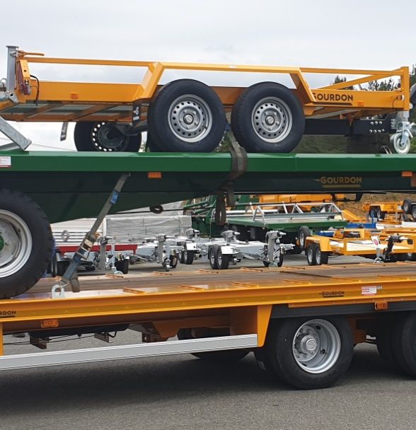 Remorque transportant des équipements agricoles sur un véhicule à plateau.